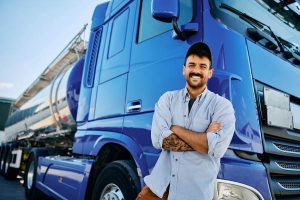 trucker posing with his blue semi truck